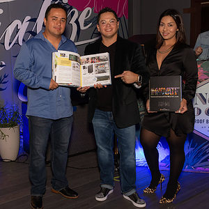 2 men and a woman in front of banner, holding an "Innovate Miami" book at "Innovate Miami" launch party.