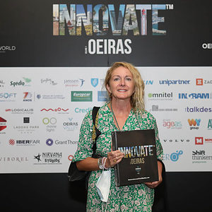 A woman in front of banner at Innovate Oeiras Launch holding Innovate Oeiras Book
