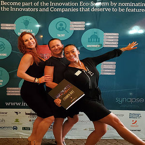 3 Women posing in front of banner, holding an "Innovate USA" book at "Innovate USA" launch party.