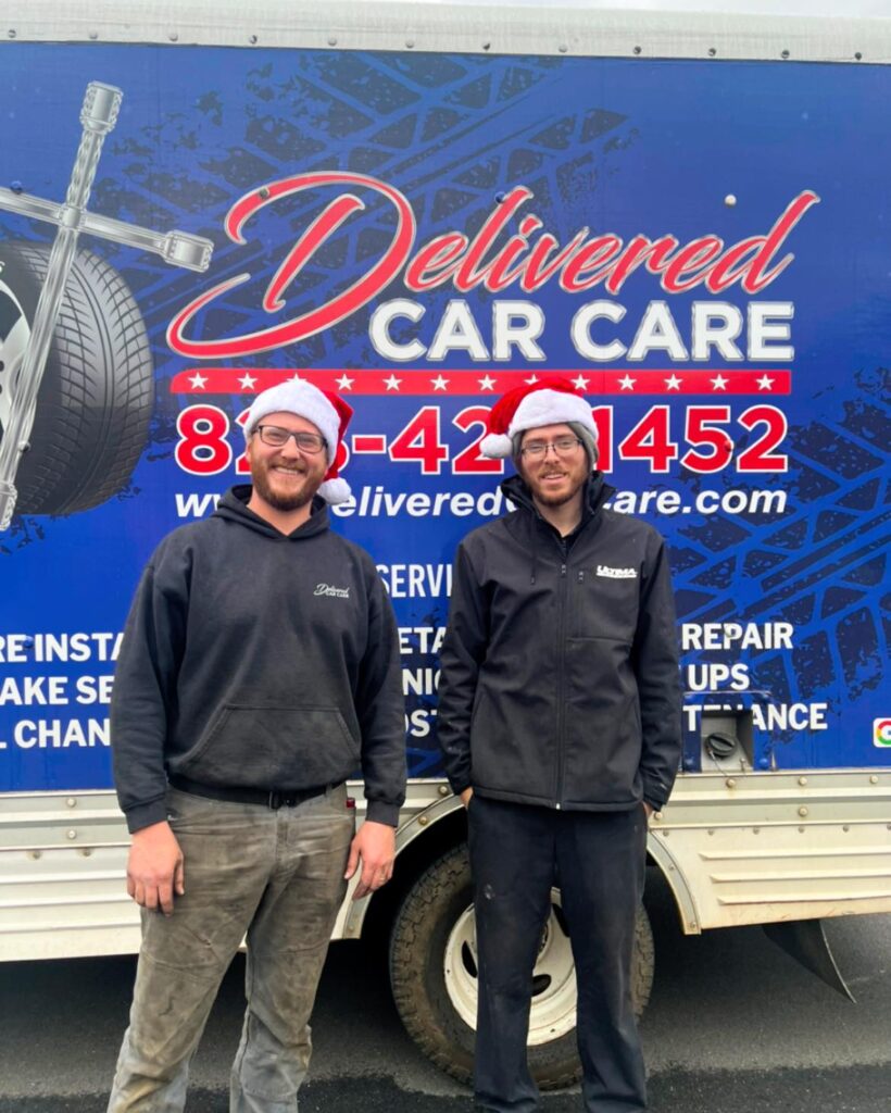 Two professional mobile tire technicians from "Delivered Car Care" standing in front of their fully branded service truck in Otto, North Carolina.