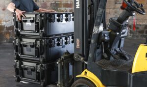 Forklift lifting stacked equipment cases.