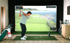 Man swinging on indoor golf simulator.