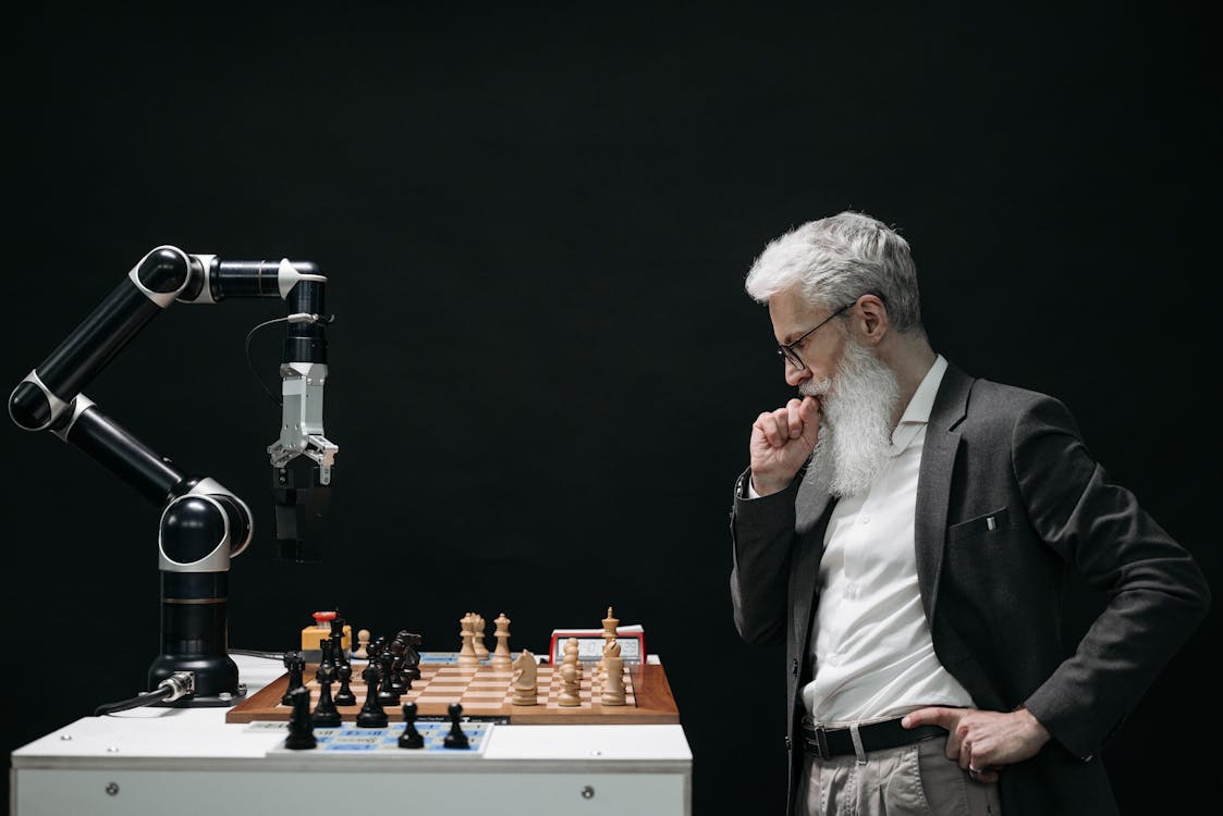 Robotic arm playing chess against a thoughtful man, representing AI as a business partner