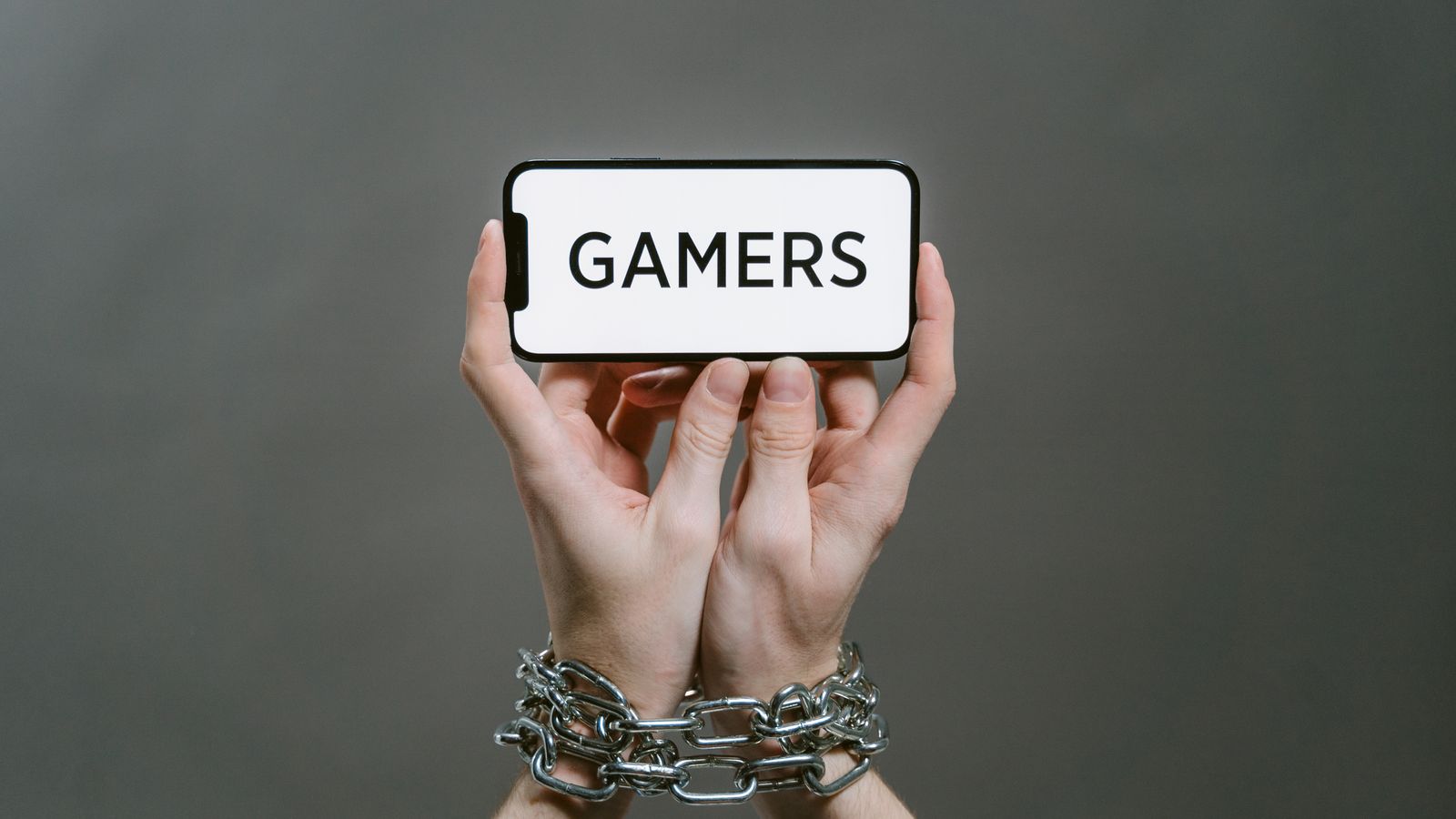 Hands in chains holding a smartphone that reads GAMERS