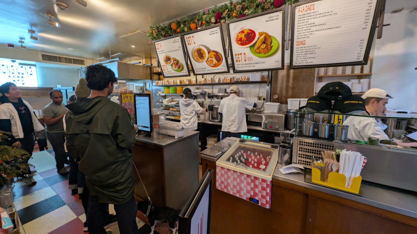 Customer ordering at a self-service touchscreen kiosk in a busy shop